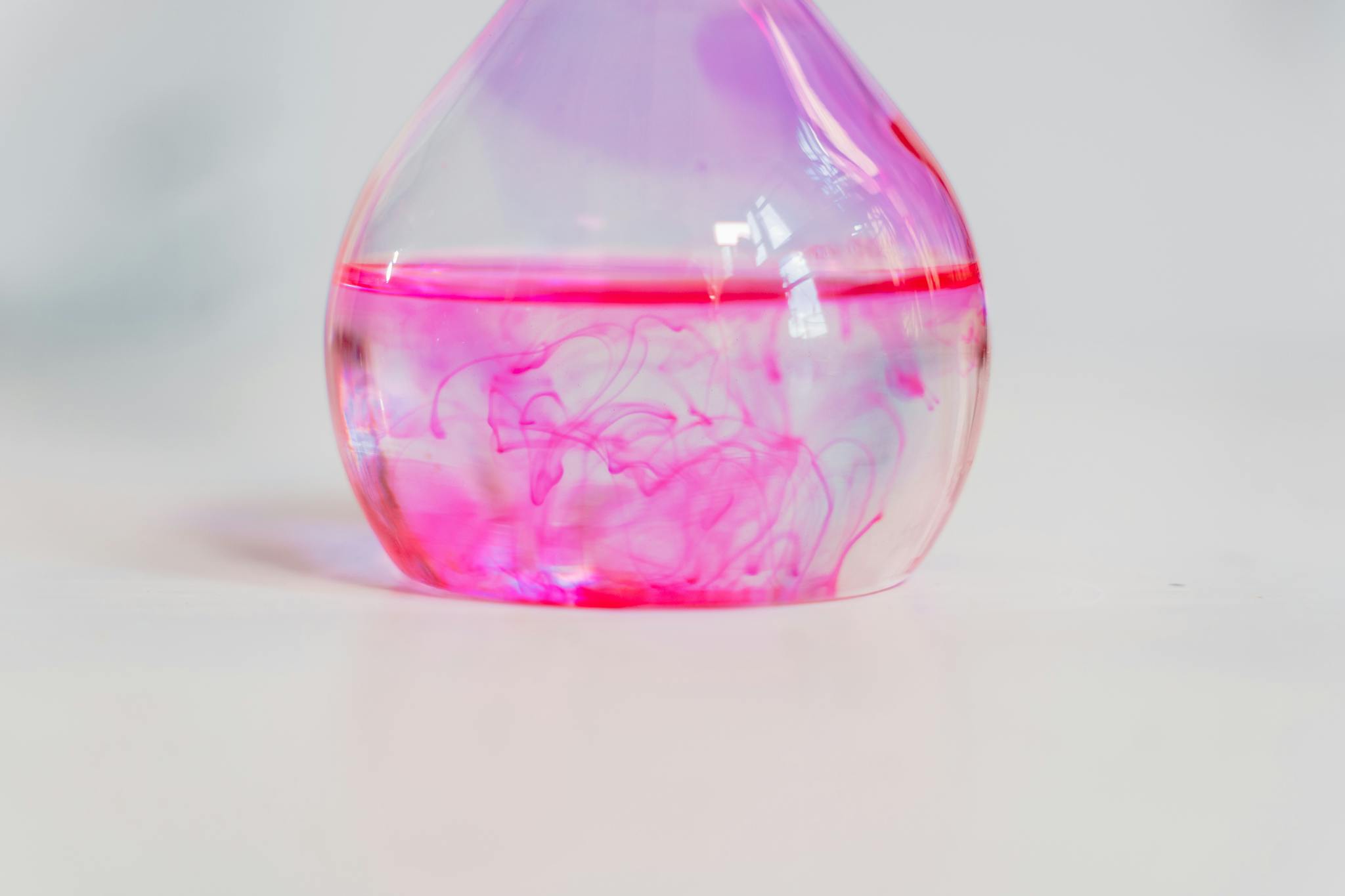 Close-up of pink dye diffusing in a laboratory flask, perfect for science and chemistry themes.